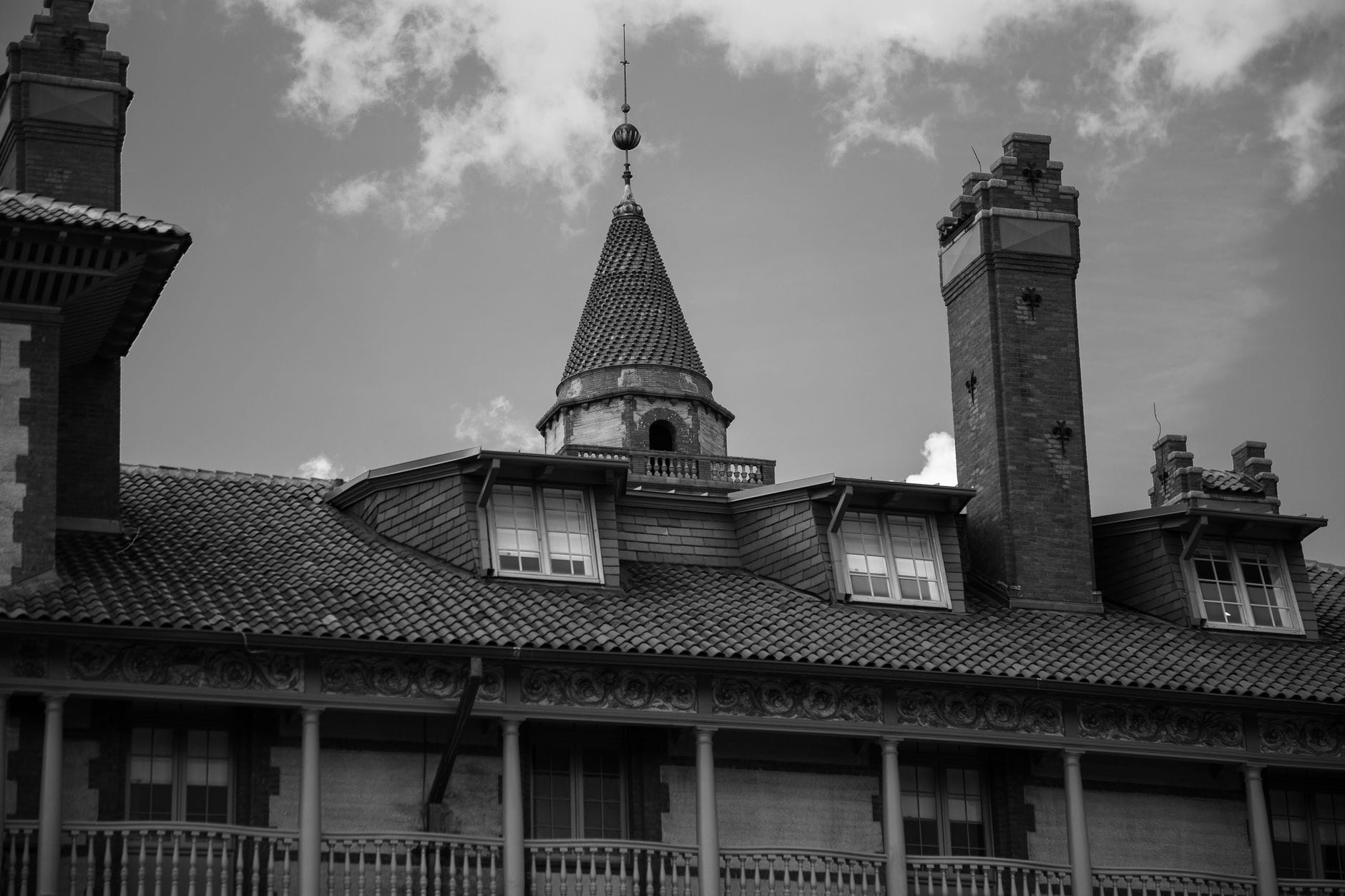 Elegant historic brick building with a pointed tower captured in monochrome.
